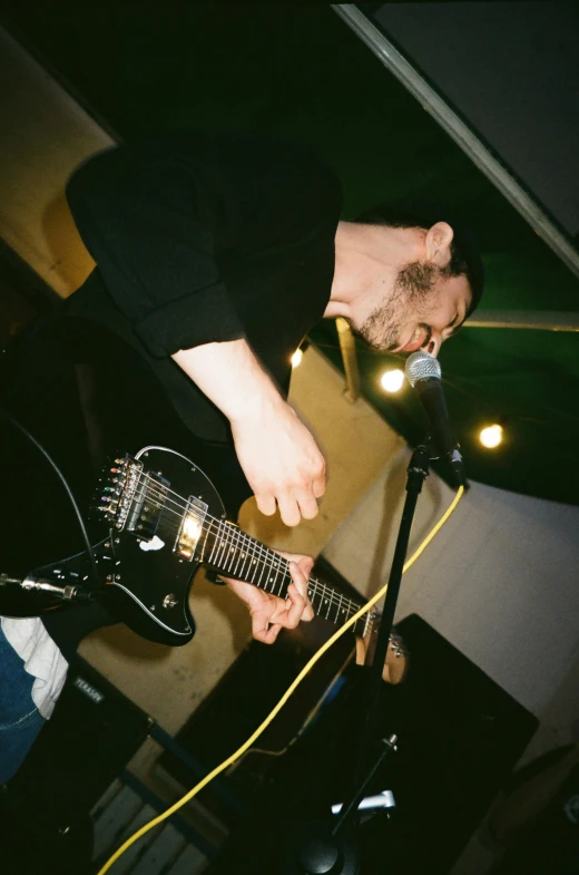 a man playing guitar by a mic in a microphone