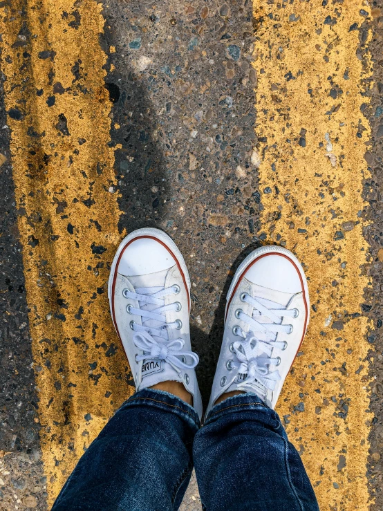 someone in white converses stands on a yellow and black grout