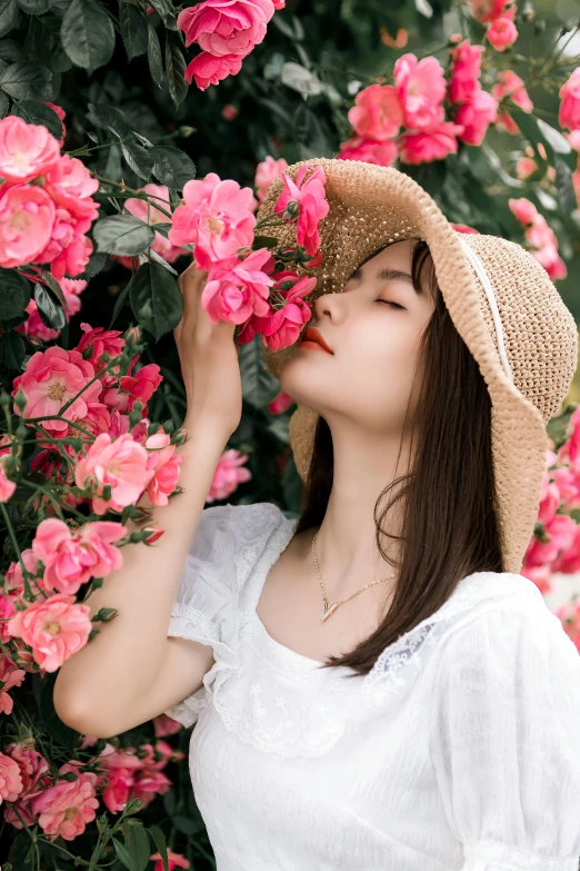 young woman smelling the beautiful pink flowers in a garden