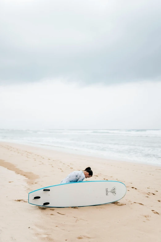 a surfer sitting in the sand with his board