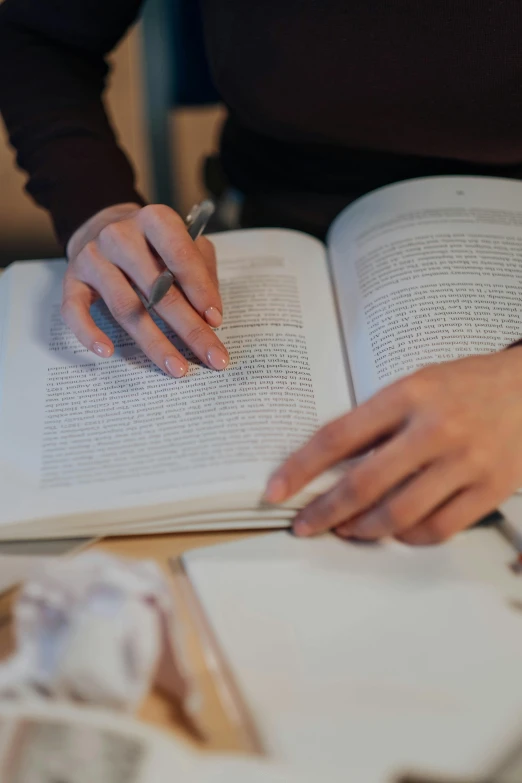 two hands with ring on open book on table