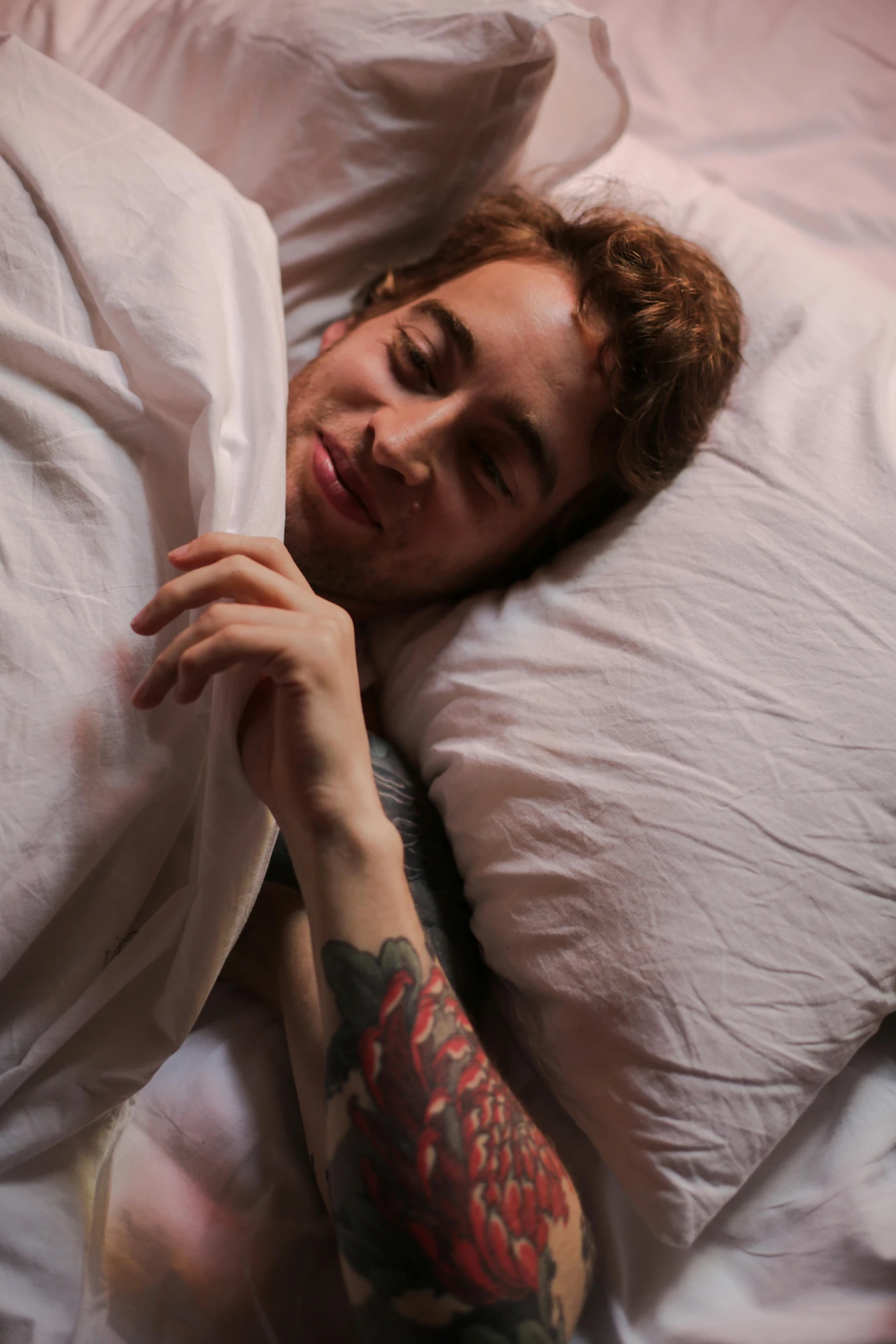 a man sleeping on a white pillow covered in pillows