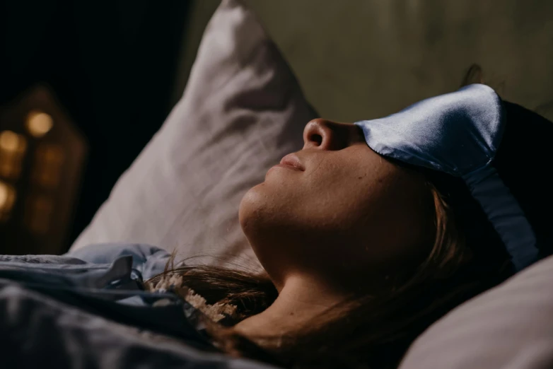 a beautiful woman laying down in bed while wearing a bow