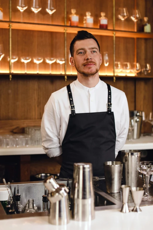 a man wearing an apron standing in front of a bar