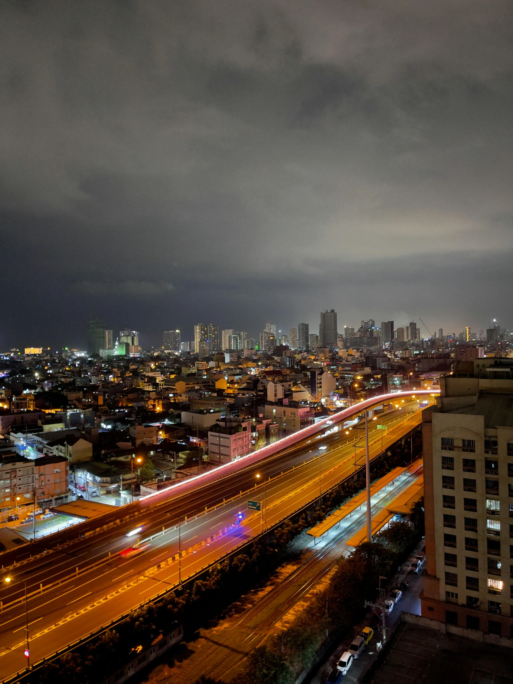 a nighttime skyline shows highway lights, city buildings and light streaks