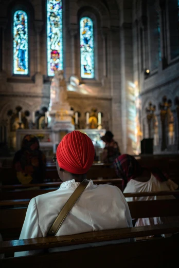 a woman sitting in the pews of a church with her red turban on
