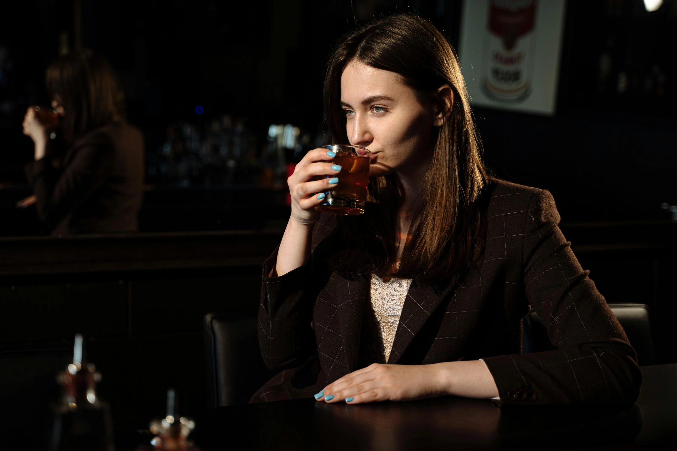 a lady sitting at a bar drinking from a glass