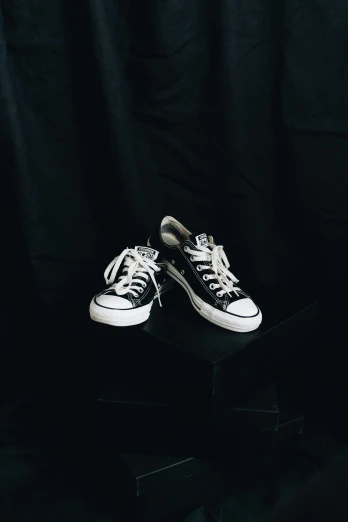 a pair of white sneakers on top of a black box