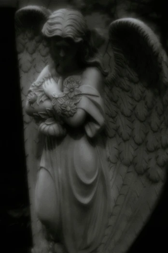 an angel statue in black and white, holding a bird