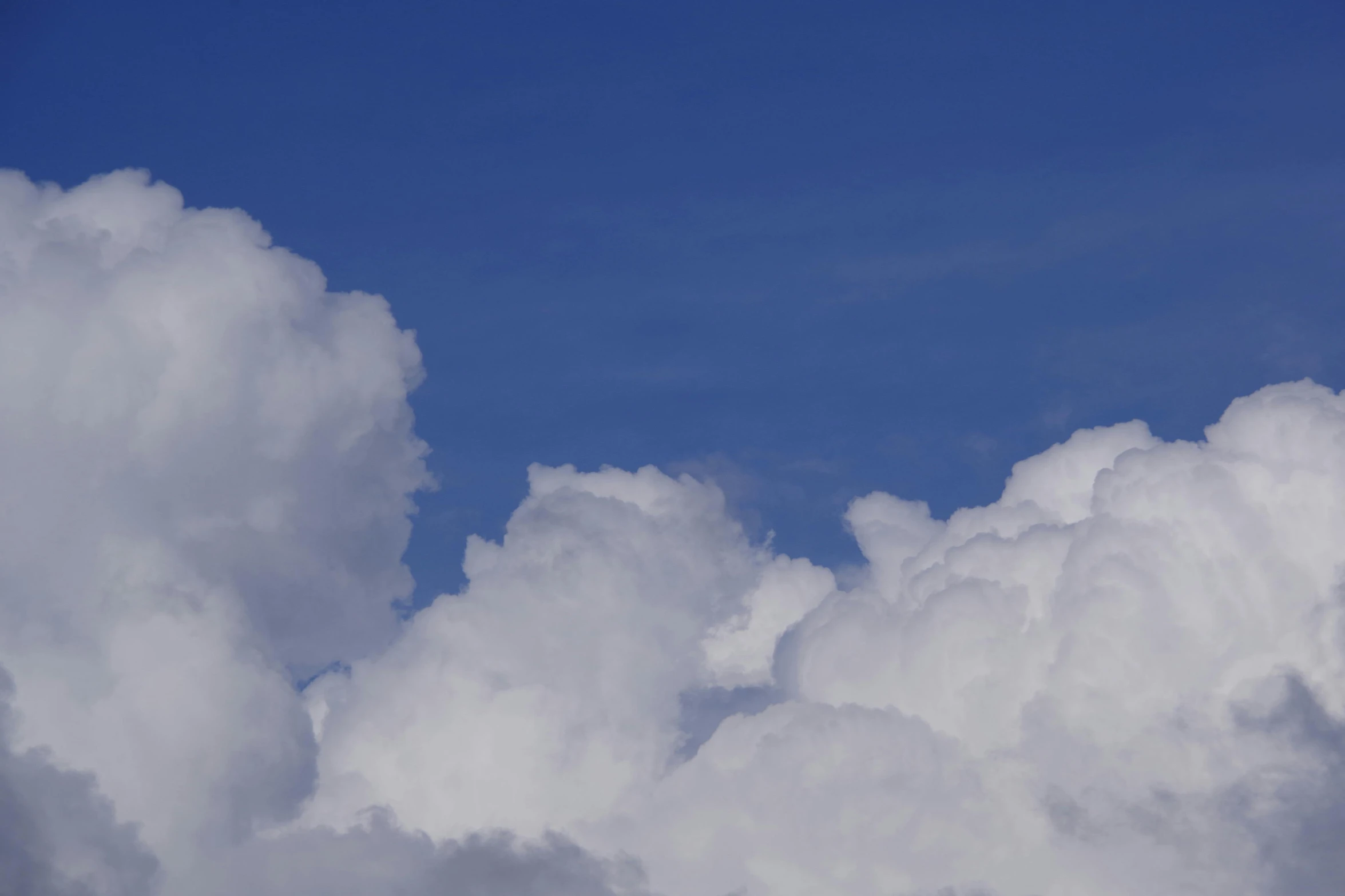 white clouds in blue sky during daytime with a plane flying