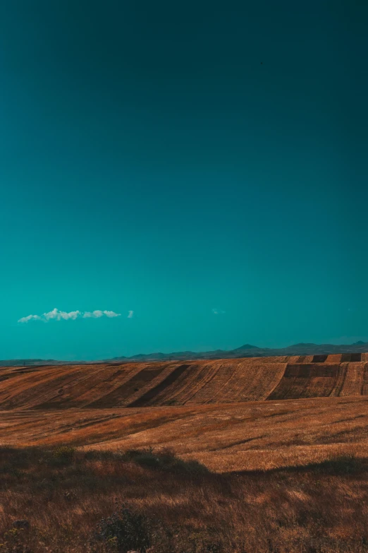 an empty field with some big bales in the distance