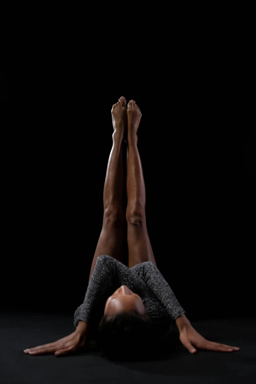 woman in grey top and black pants doing a handstand