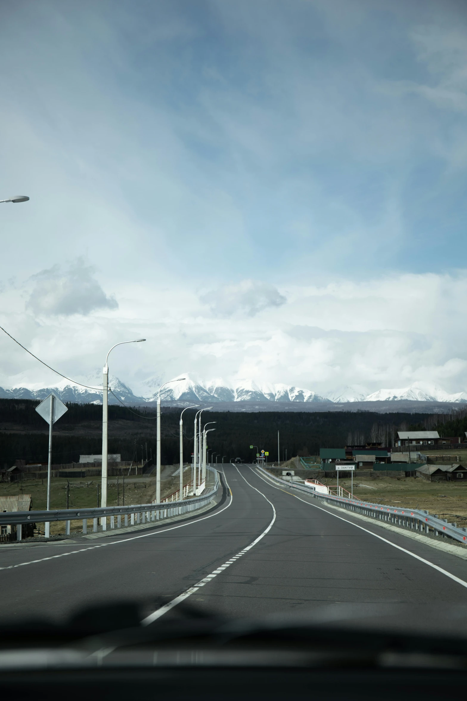 an empty highway near a mountain range under the blue sky