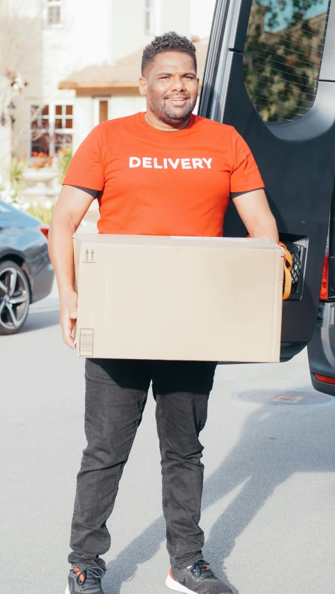 a man standing next to a van holding a large box