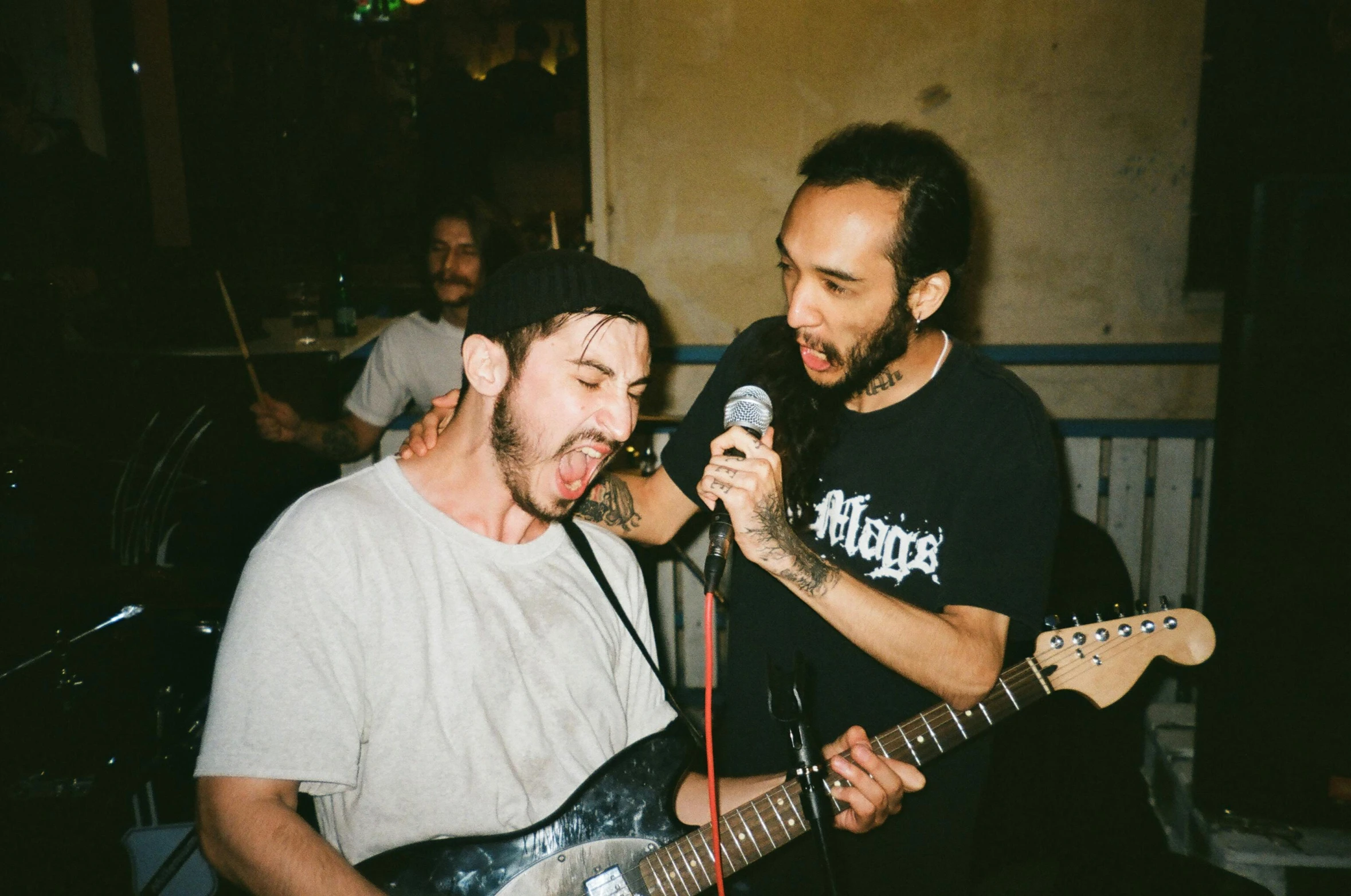 two young men with guitars playing an acoustic show