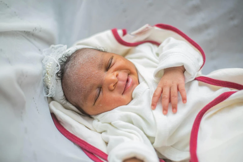 a newborn baby sleeps while wrapped in white