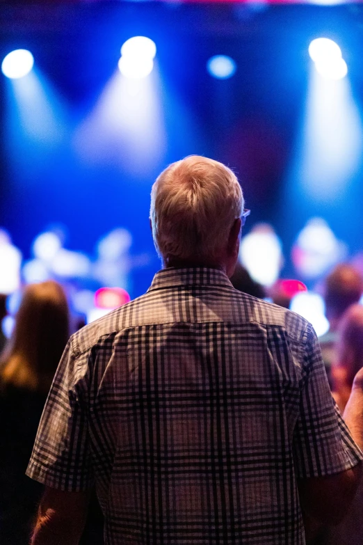 a man is holding his arms out to the crowd in front of the stage