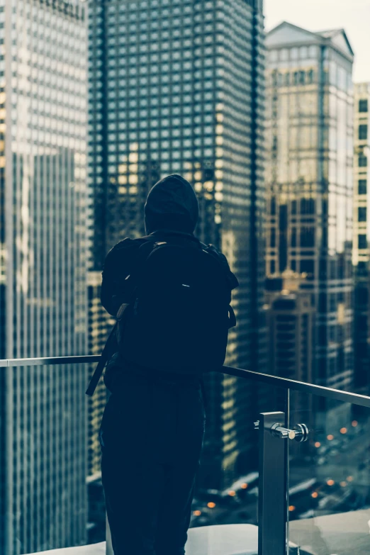 a person standing on the edge of a tall building looking at skyscrs
