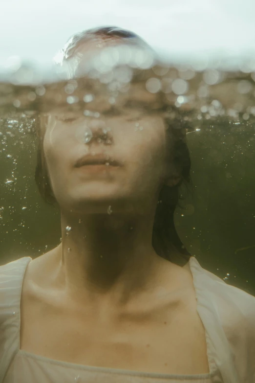 a woman floating in a pond with water droplets