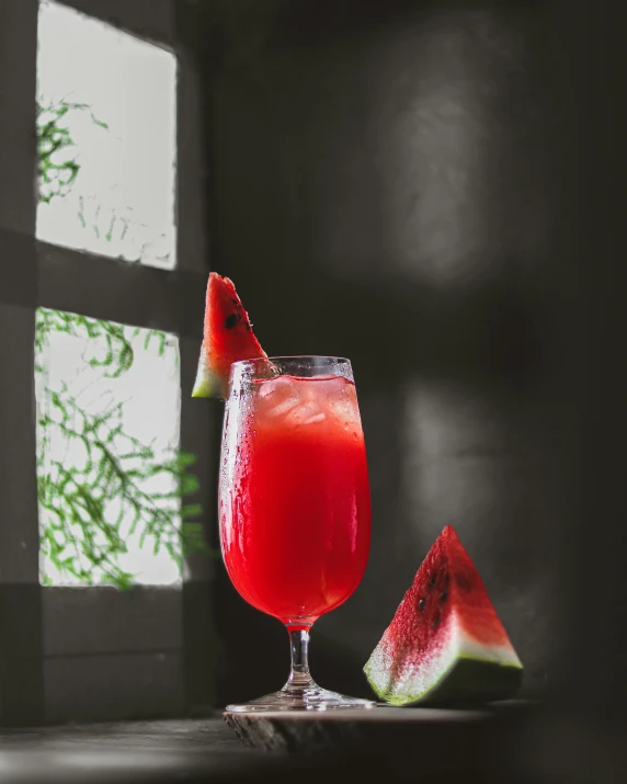 a close up of a wine glass near a slice of watermelon