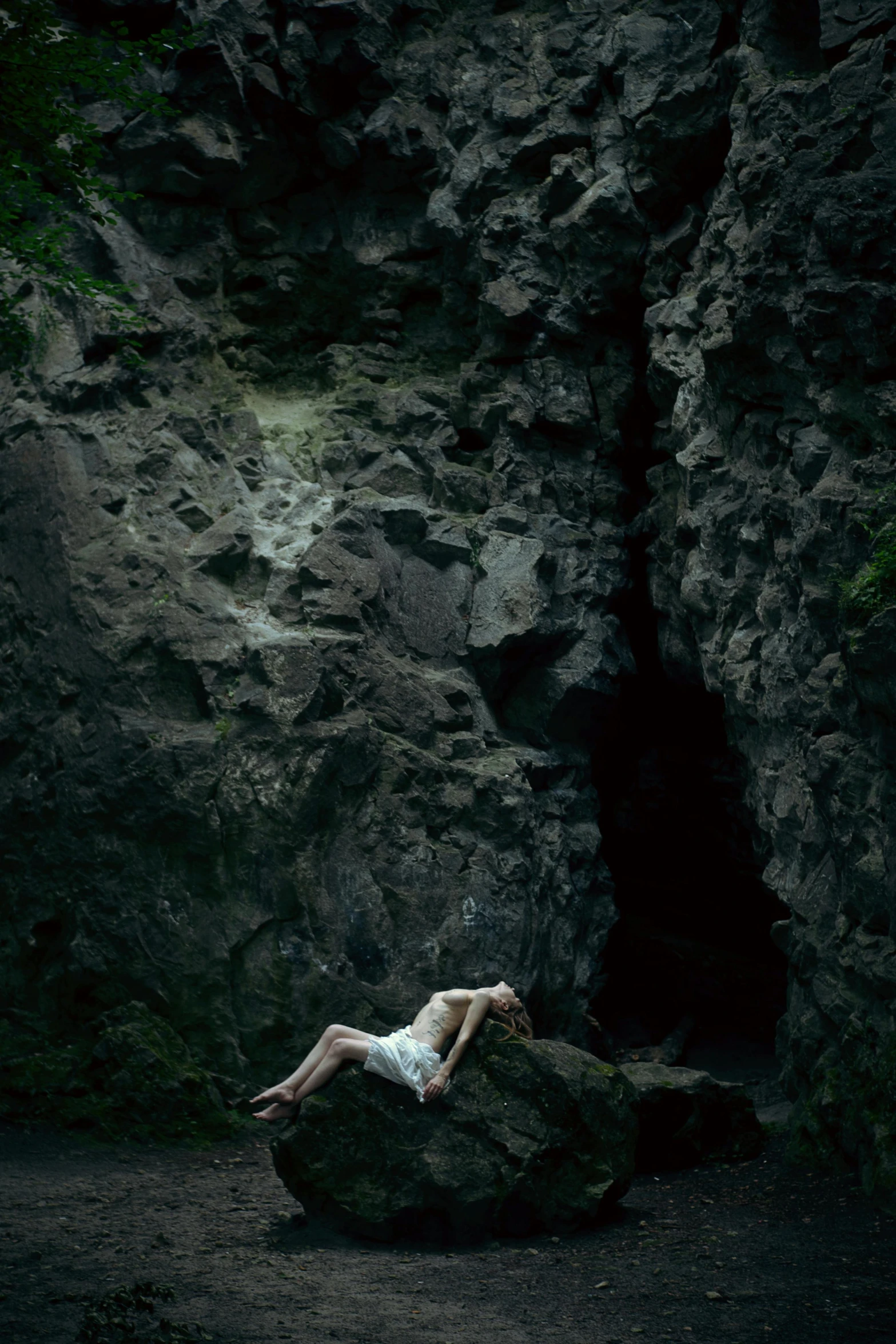 a woman in a white dress is laying on top of rocks