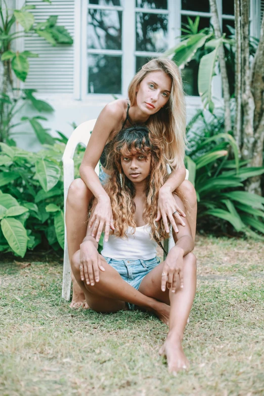 two young women sit on a lawn chair