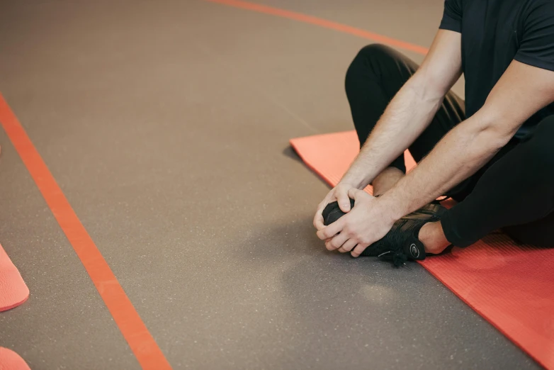 a man kneels on the ground while fixing his shoe