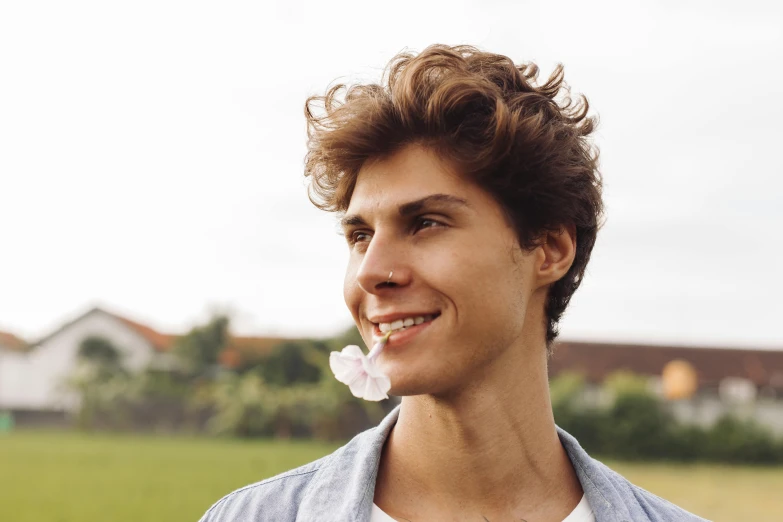 a young man is posing with a flower in his mouth