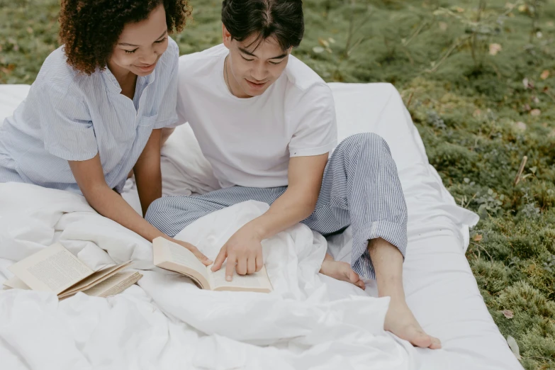 two people sit on the ground reading books