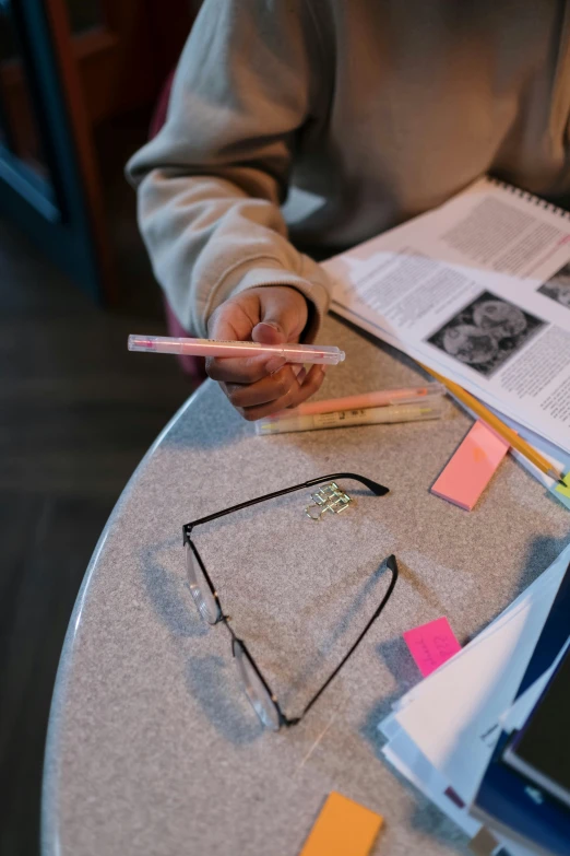 a person holding a pencil while sitting at a table