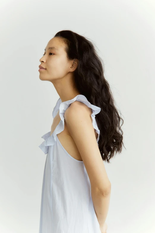 the model wears a white ruffle - detailed tank