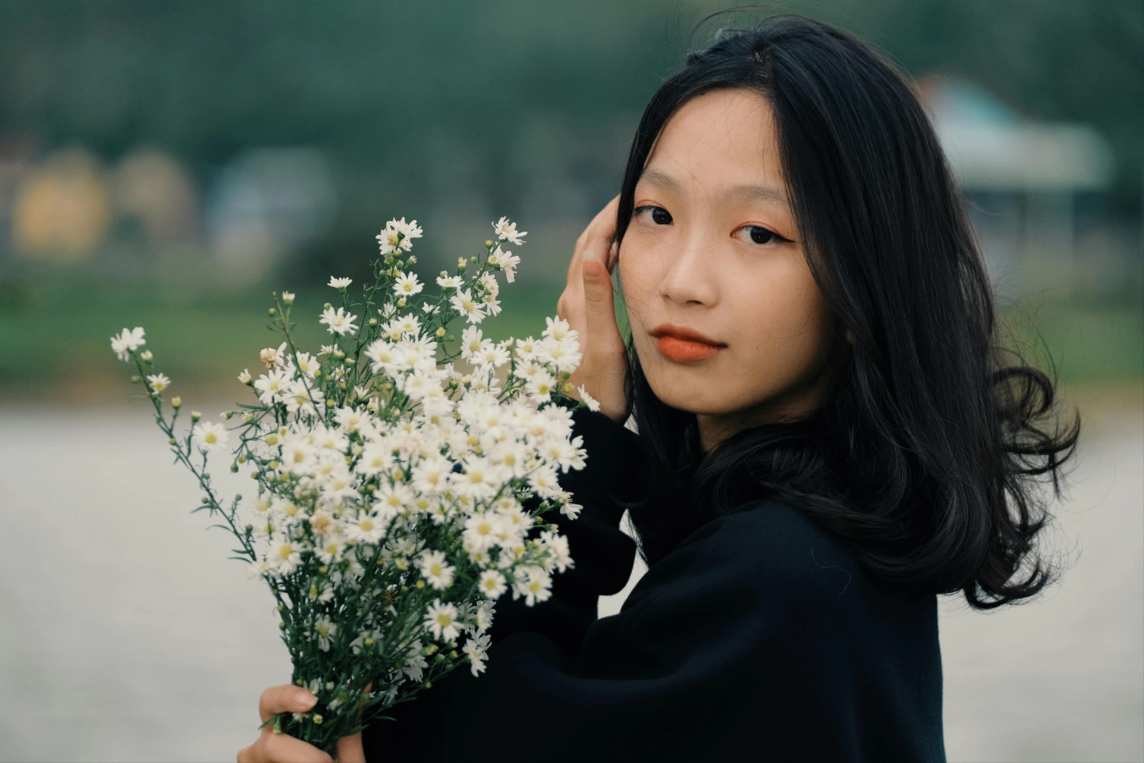 a woman holding some white flowers in her hand