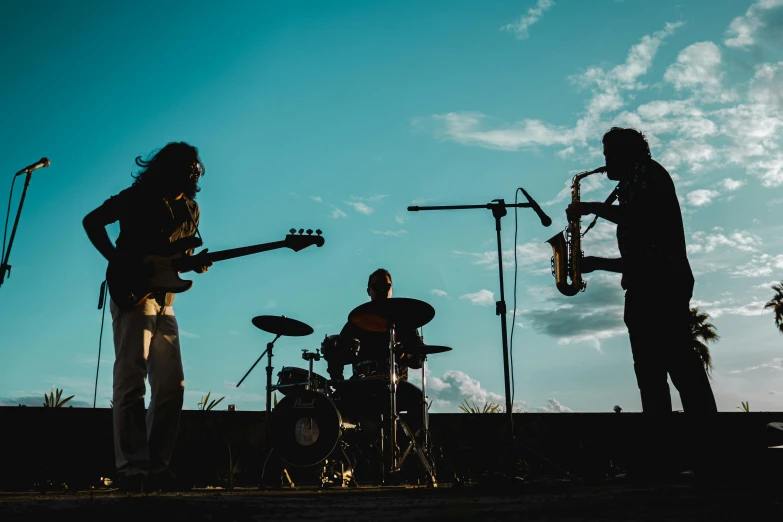 three musician on stage while their guitarist plays in front