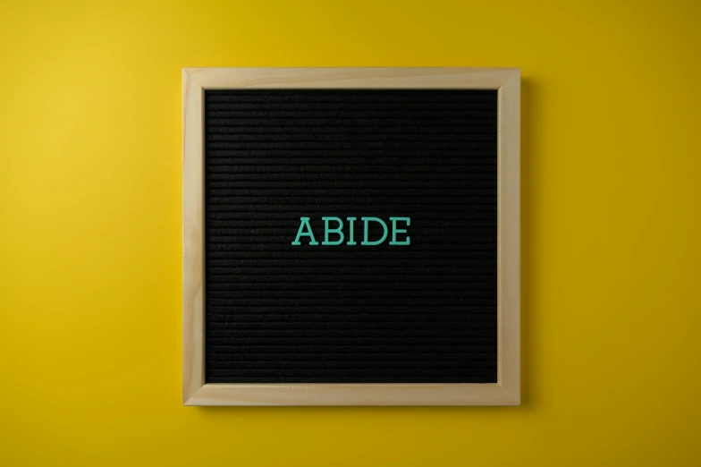 black and green text that says abide on a yellow wall