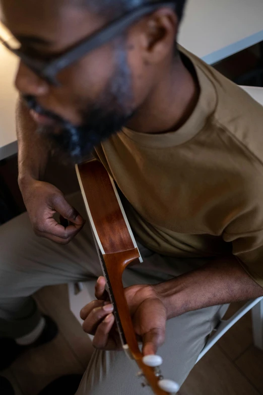 man playing guitar, adjusting strap to guitar