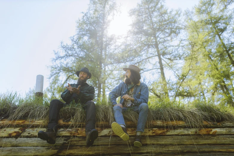 two men sitting on logs in the woods