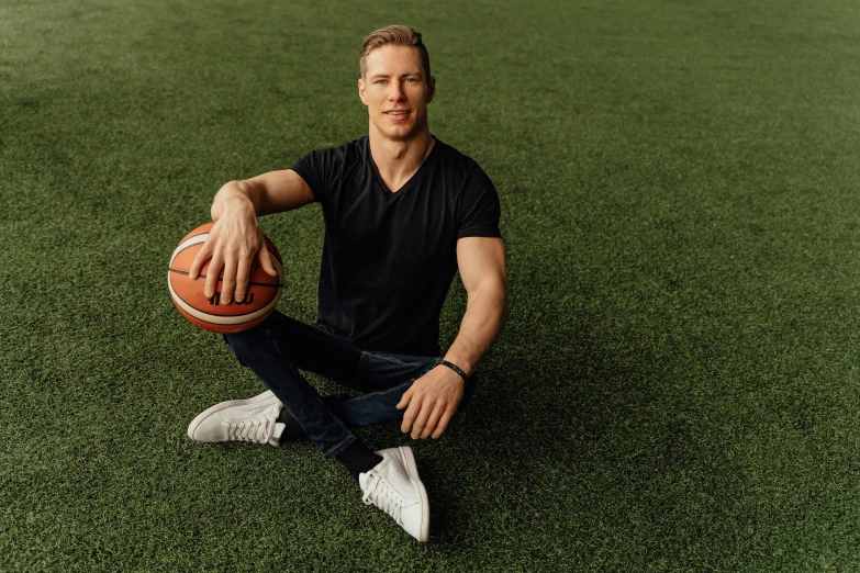 a man kneeling in the grass with a basketball