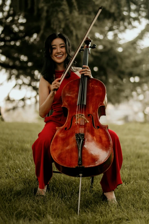 the woman is playing on her cello in the grass