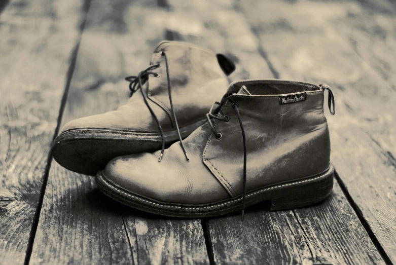 an old pair of shoes is on a wooden surface