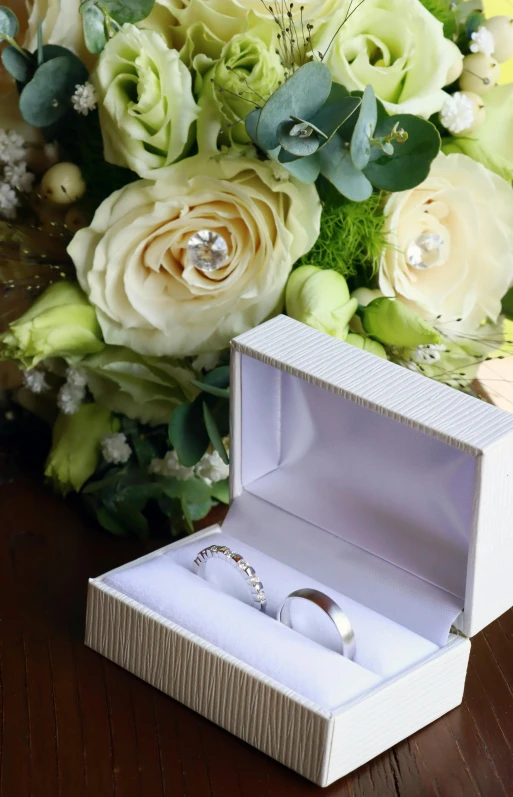 two white roses and wedding rings in an opened box