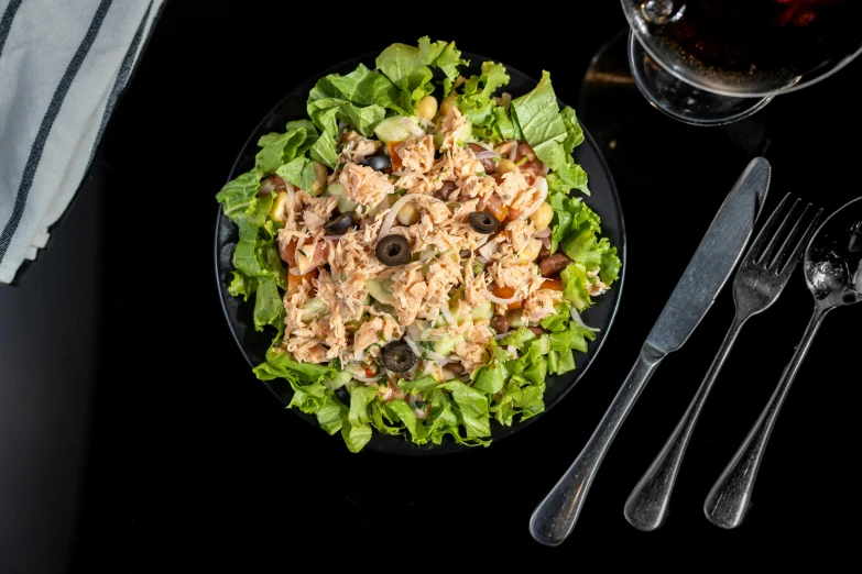 salad and cutlery sit on a black surface