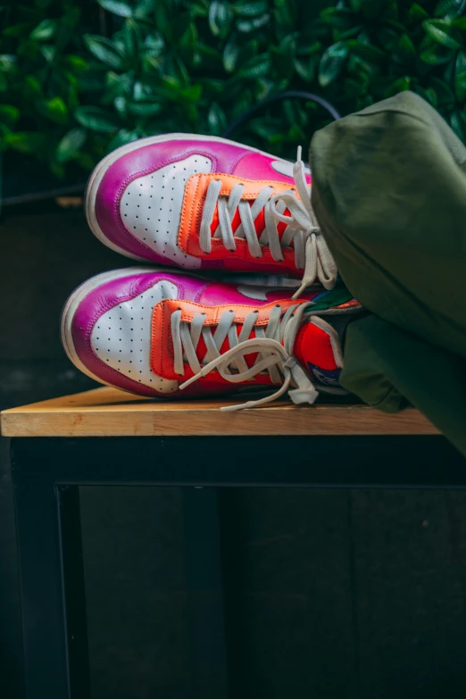 there is a pair of pink sneakers that are sitting on a wooden table