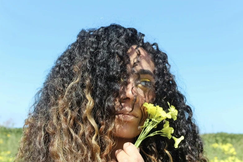 a woman holds up a yellow flower to her face