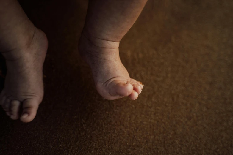 a small infant's toes and ankles, with a little boy's paw hanging from the top of it