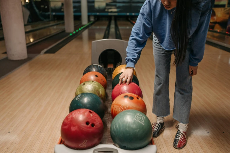 a woman placing seven bowling balls onto a roller