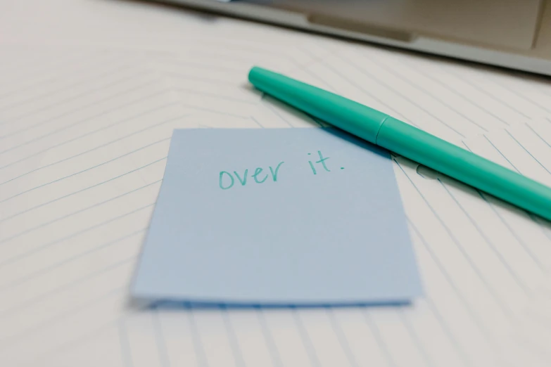 an open notebook and a green pen on a white table