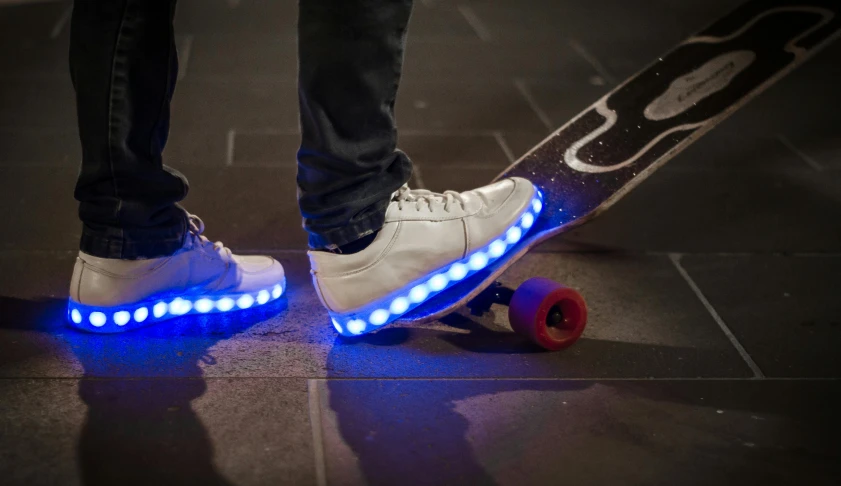 a person with white shoes on with lights on top of the skateboard