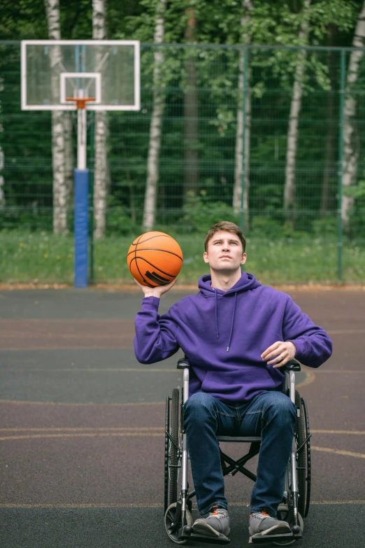 a man in a wheelchair holds a basketball up to his face