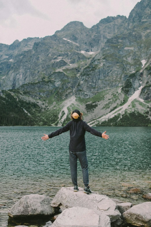 a man stands on top of rocks by the water