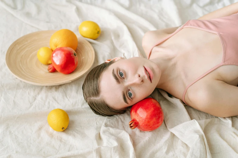 a man in a bathing suit laying on a bed with apples and lemons